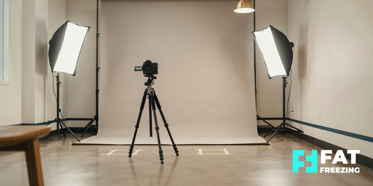 Camera on a tripod facing a plain backdrop between two softbox lights.